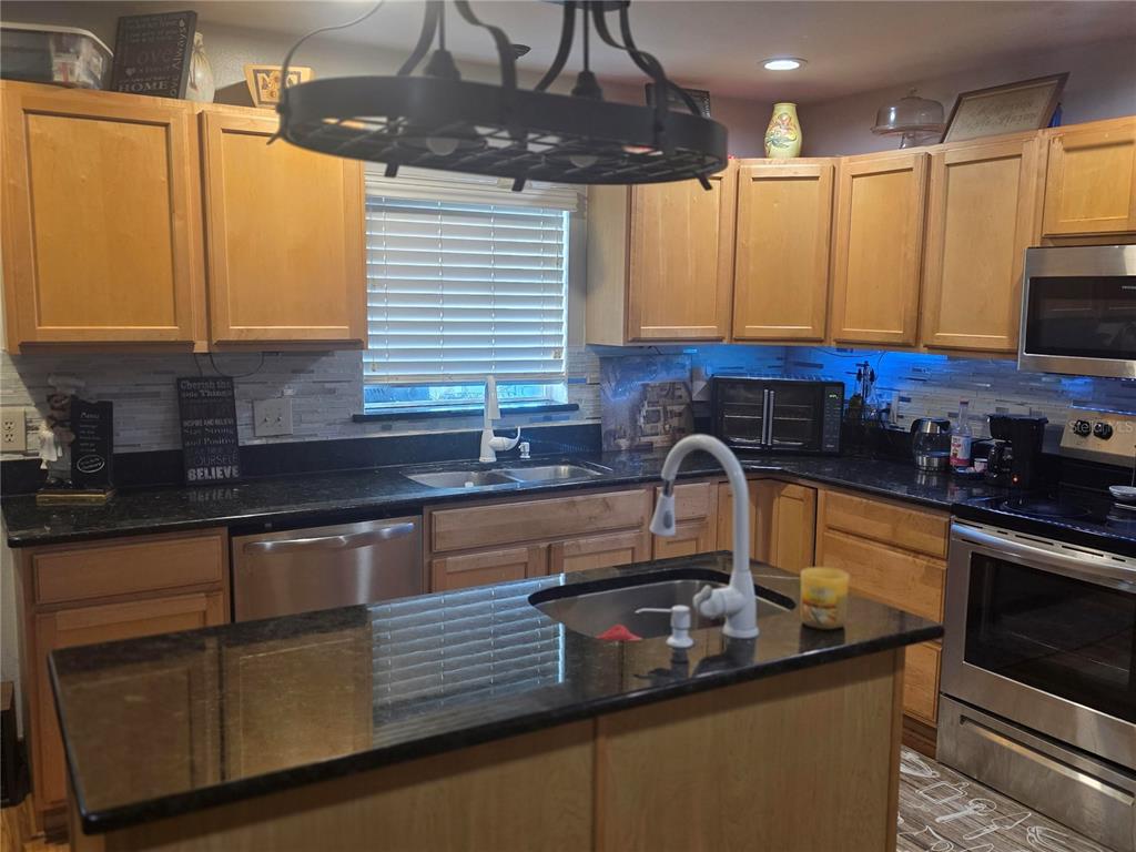 959 Thomas Road Eagle Lake, FL 33839 - Photo 9 of 35 a kitchen with stainless steel appliances granite countertop a sink a stove and a wooden cabinets