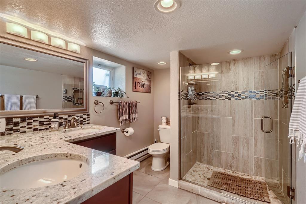 4140 Decatur Street Denver, CO 80211 - Photo 21 of 33 a bathroom with a granite countertop sink a toilet a mirror and shower