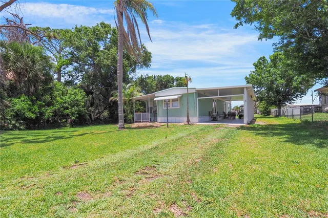 a view of a house with a big yard and large trees