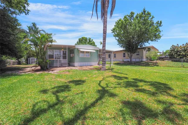 a view of a house with a big yard and palm trees