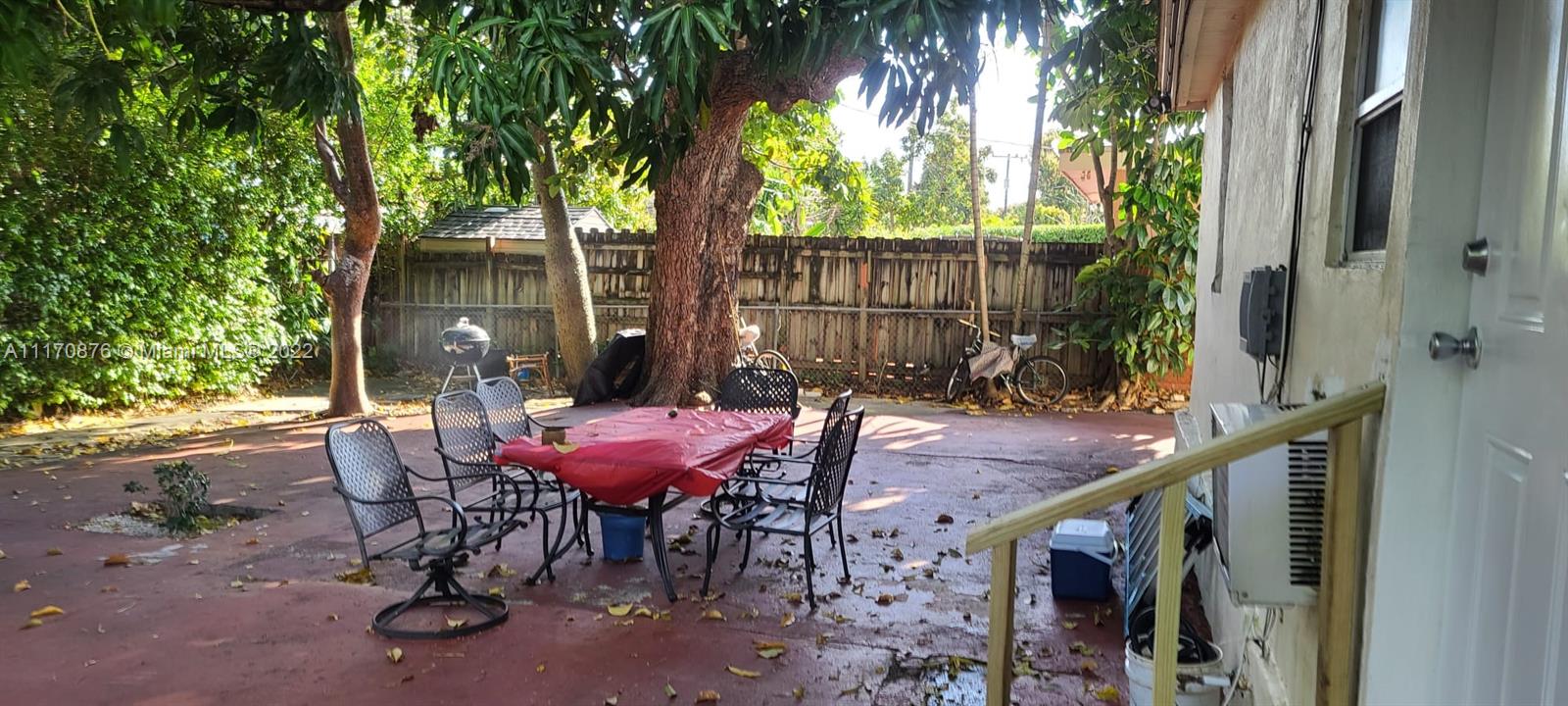 4001 Northwest 3rd Street Miami, FL 33126 - Photo 4 of 17 a view of a patio with table and chairs with wooden fence and large trees