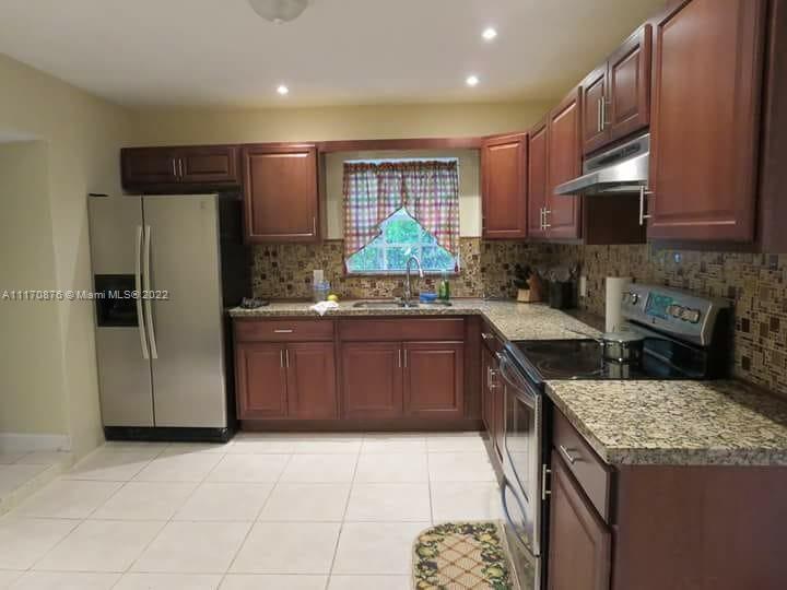 4001 Northwest 3rd Street Miami, FL 33126 - Photo 9 of 17 a kitchen with stainless steel appliances granite countertop a stove a sink and a refrigerator