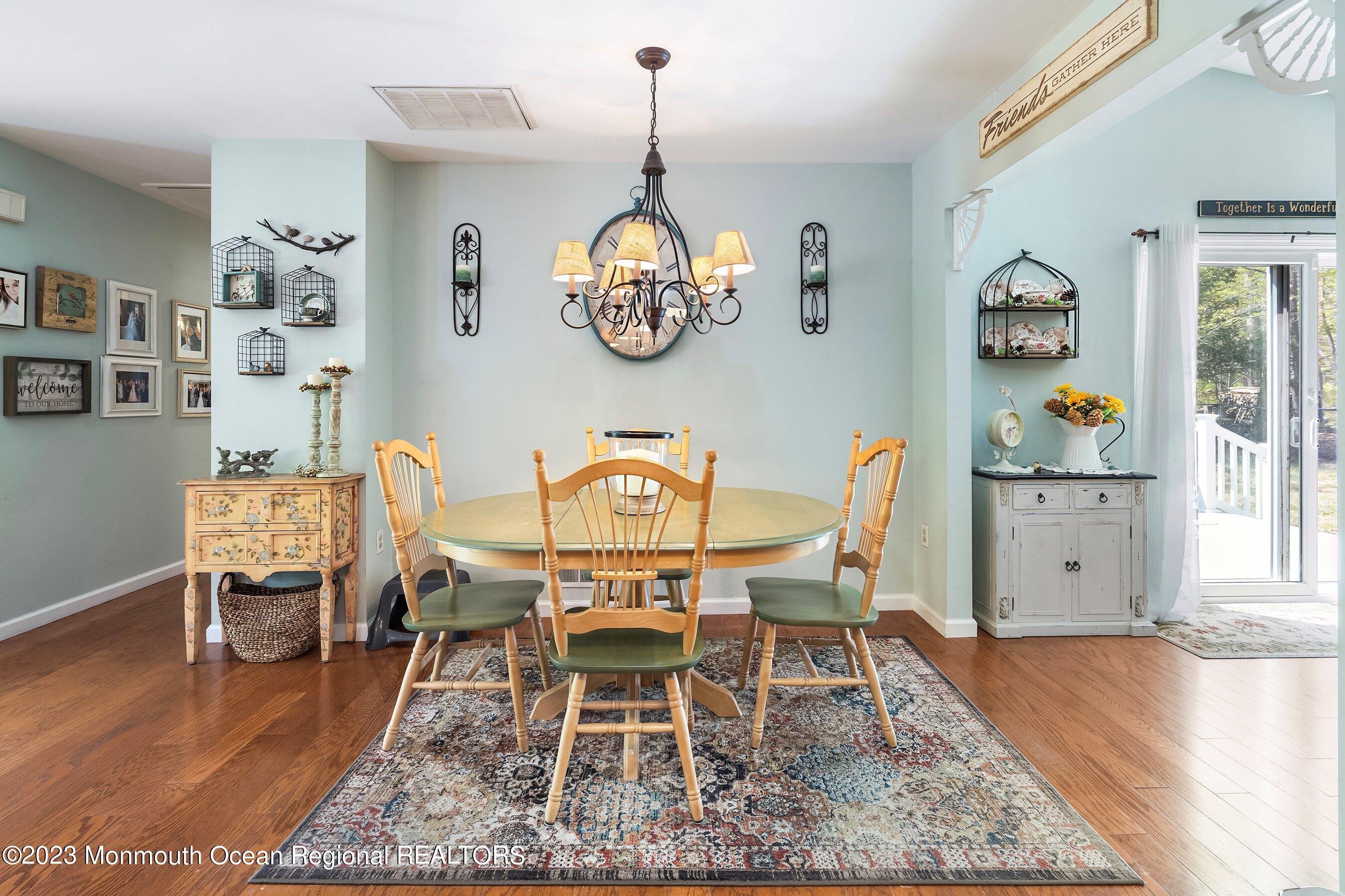 370 Constitution Drive Forked River, NJ 08731 - Photo 14 of 25 a dining room with wooden floor a chandelier a wooden table and chairs