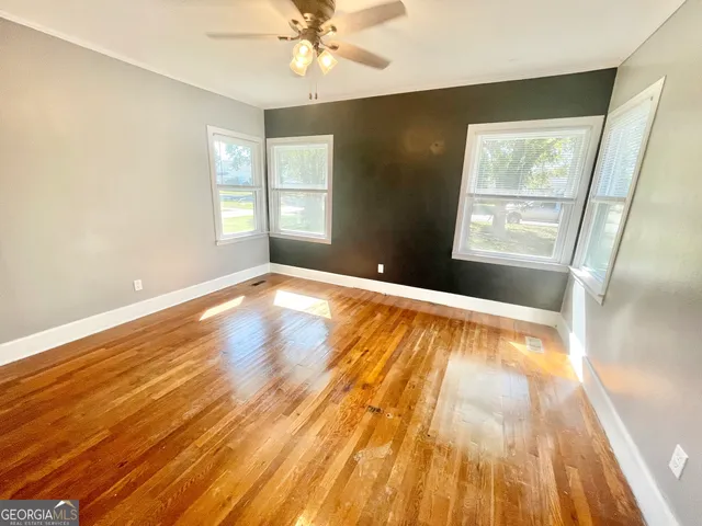 a view of an empty room with wooden floor and a window