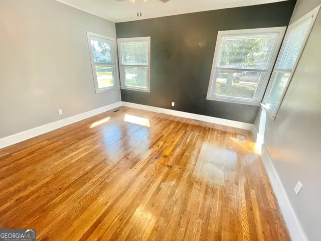 a view of an empty room with wooden floor and a window