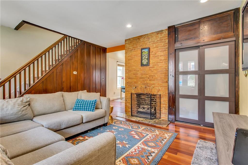 705 Filbert Street Pittsburgh, PA 15232 - Photo 7 of 25 Exposed brick, fireplace, and coat closet can be seen in this photo, with a peek into the kitchen/dining room.