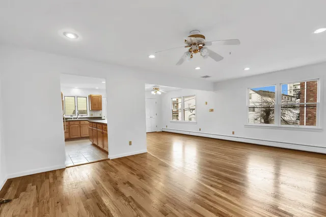 an empty room with wooden floor chandelier and windows