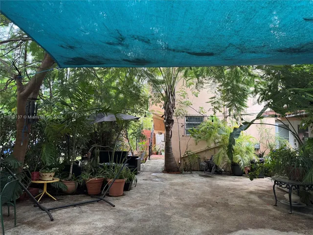 a view of a patio with table and chairs potted plants and large tree