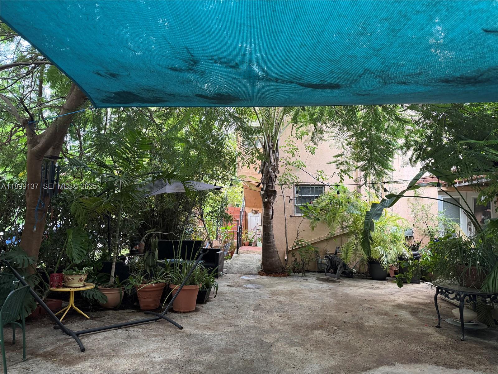 a view of a patio with table and chairs potted plants and large tree