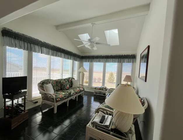 a living room with furniture floor to ceiling window and a flat screen tv