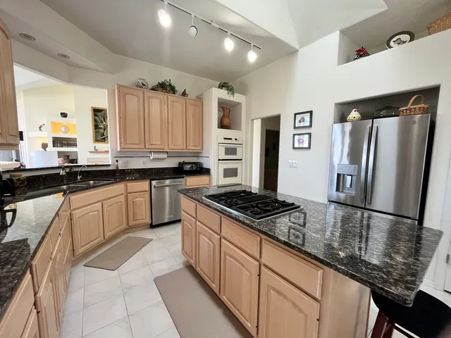a kitchen with stainless steel appliances granite countertop a sink stove refrigerator and cabinets