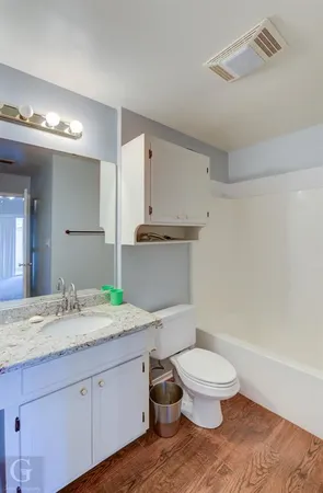 a bathroom with a granite countertop sink a toilet and a mirror