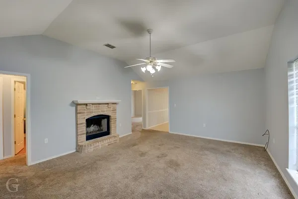 a view of an empty room with a fireplace and chandelier fan