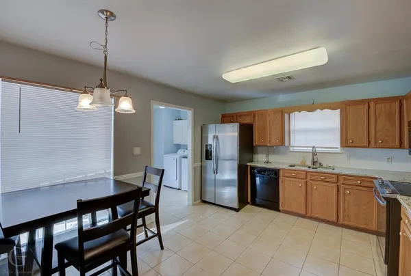a kitchen with stainless steel appliances granite countertop a dining table chairs and a refrigerator