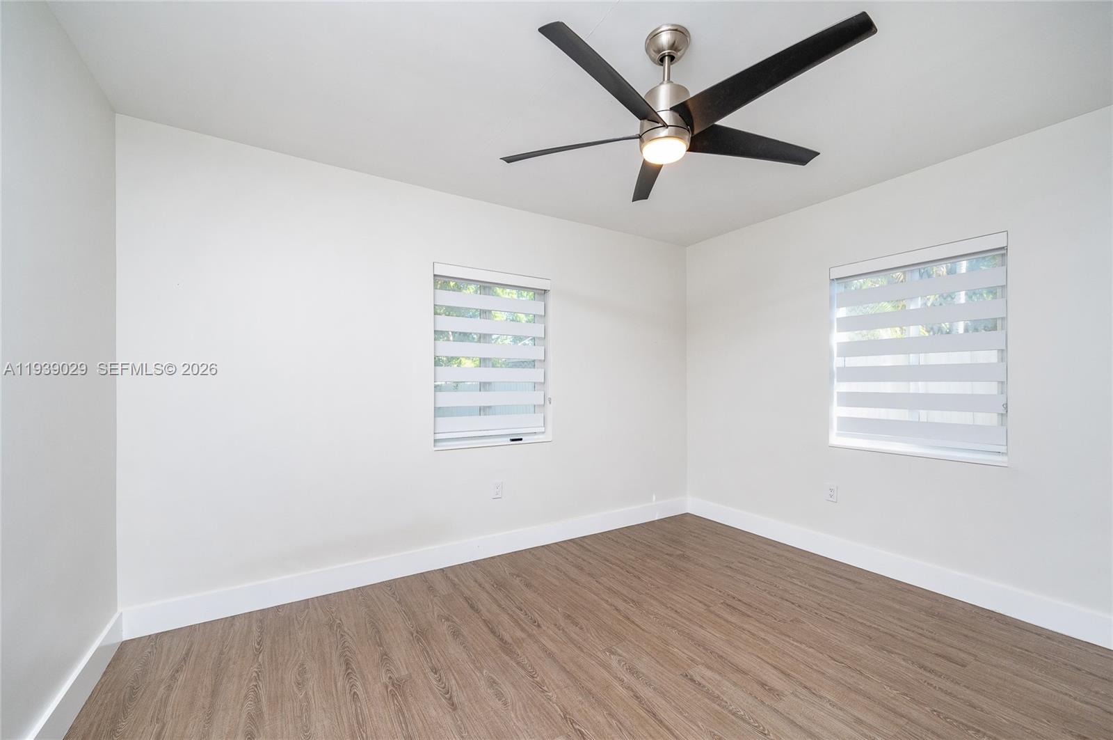 3077 Southwest 5th Street Miami, FL 33135 - Photo 21 of 25 an empty room with wooden floor ceiling fan and windows