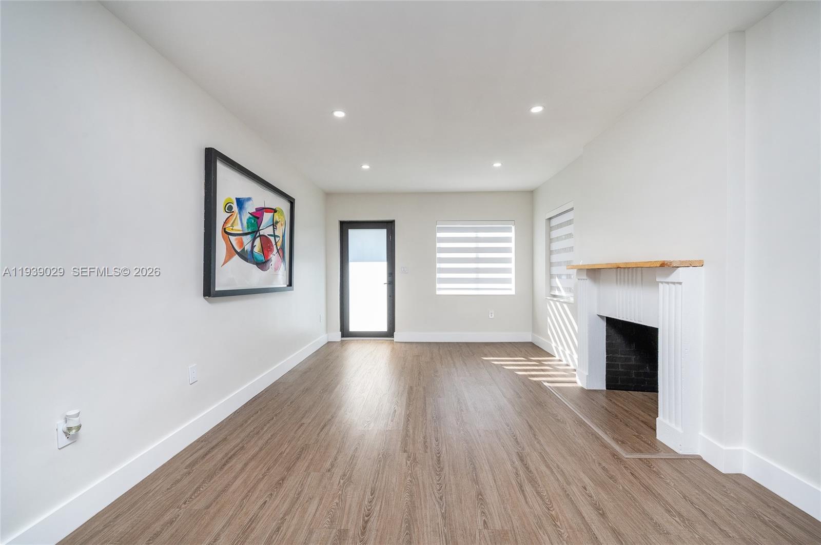 3077 Southwest 5th Street Miami, FL 33135 - Photo 7 of 25 an empty room with wooden floor fireplace and windows