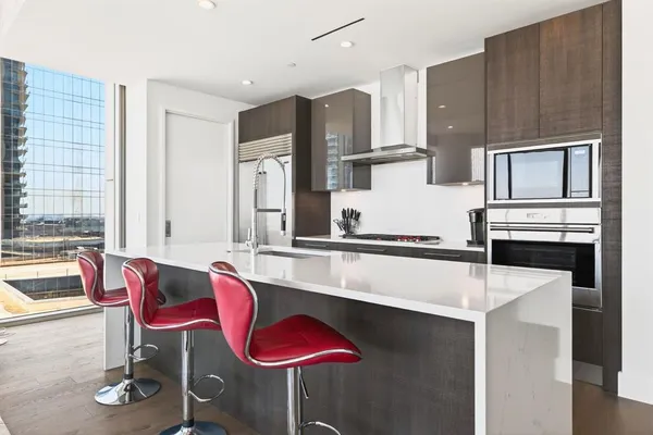 a kitchen with stainless steel appliances kitchen island granite countertop a table chairs and a refrigerator