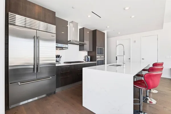 a kitchen with stainless steel appliances kitchen island granite countertop a refrigerator and a sink