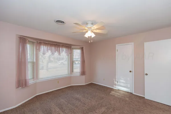 an empty room with a window and a fan