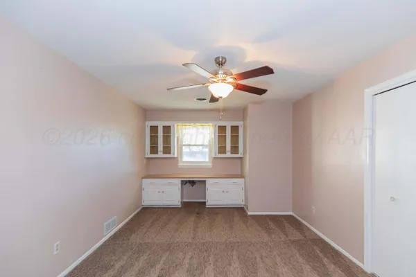 a view of an empty room with window and cabinet