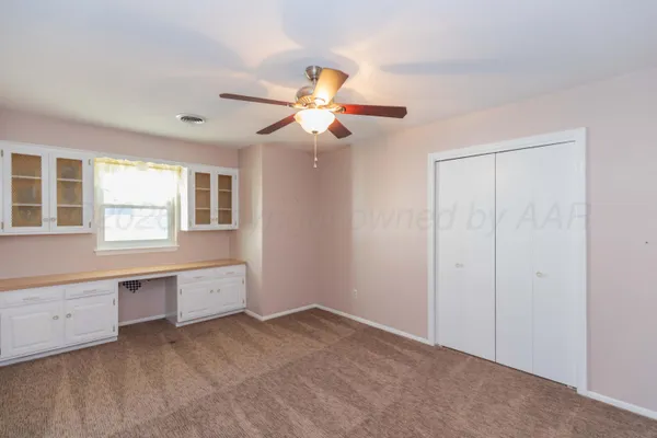 an empty room with a chandelier fan and a bathroom