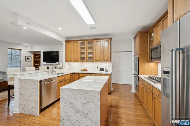 a kitchen with stainless steel appliances kitchen island granite countertop a stove top oven a sink a dining table and chairs