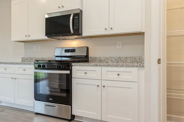 a kitchen with stainless steel appliances granite countertop white cabinets and a stove a oven with white countertops