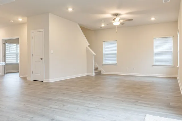 an empty room with wooden floor and windows