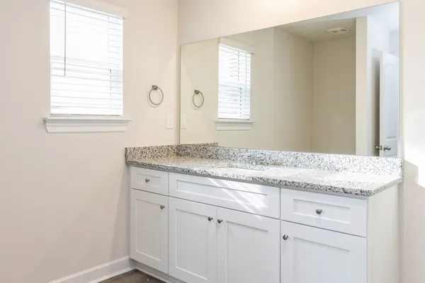 a bathroom with a granite countertop sink and a window