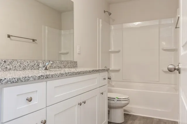 a bathroom with a granite countertop sink a toilet and shower