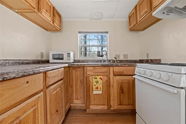 a hallway with a stove a microwave oven and a dining table with wooden floor