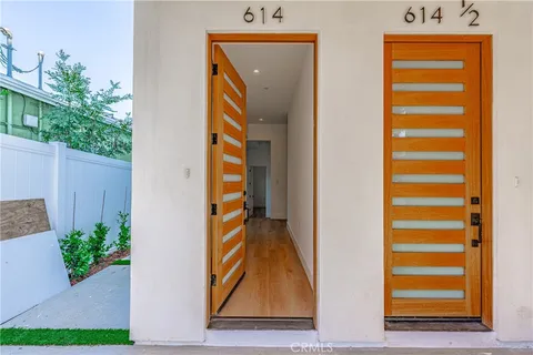 a view of an empty room with wooden floor and a hallway
