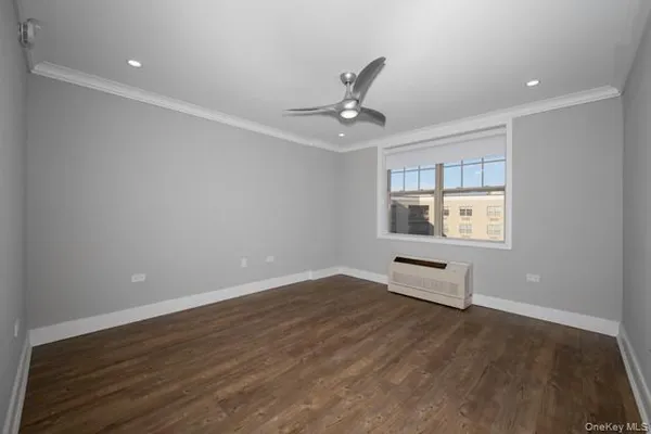 an empty room with wooden floor chandelier fan and windows