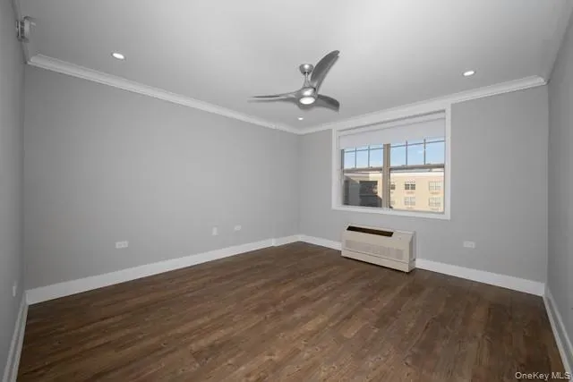 an empty room with wooden floor chandelier fan and windows