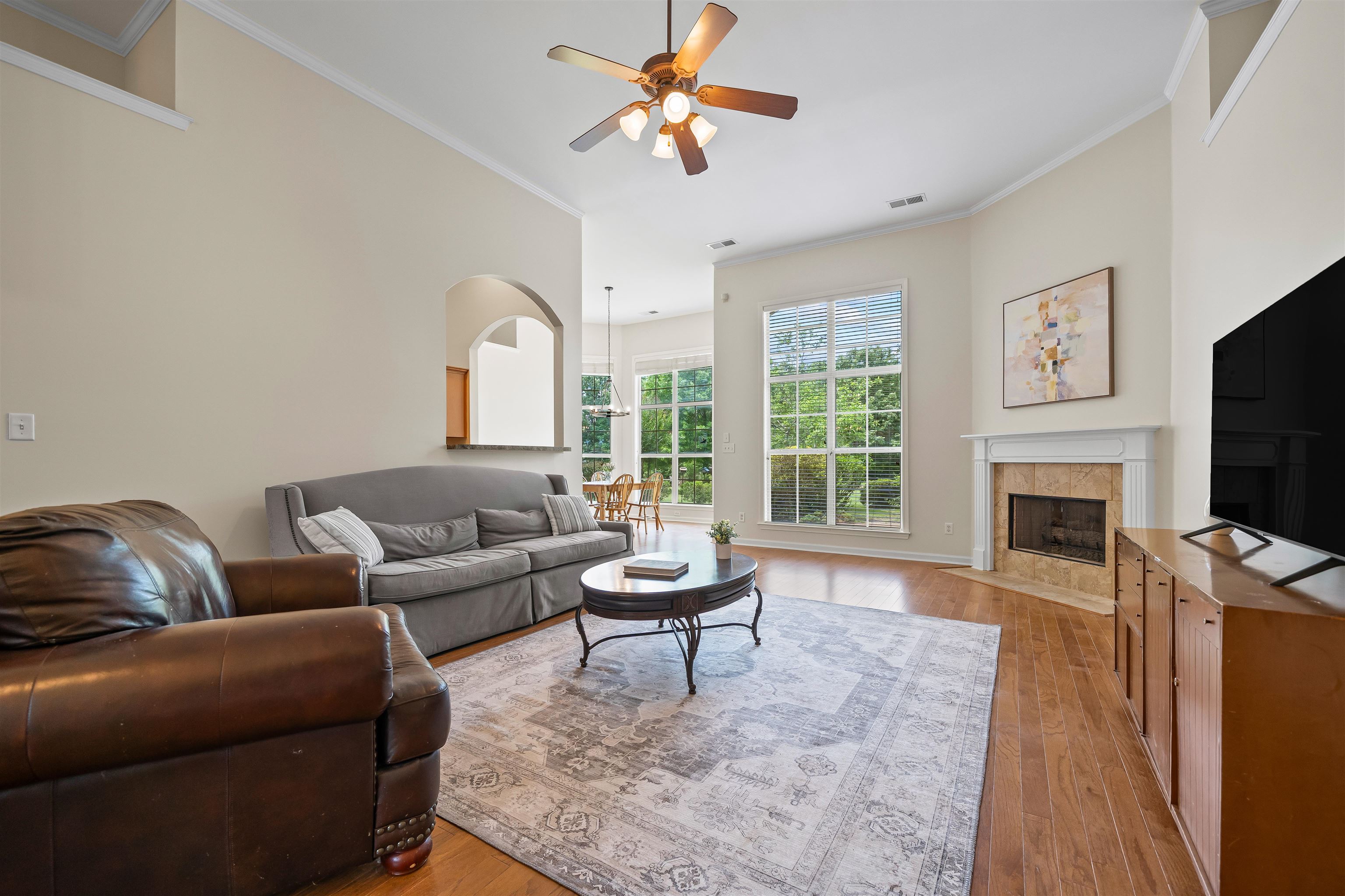 5035 Brian Ridge Road Arlington, TN 38002 - Photo 13 of 40 Vaulted living area featuring wood-finish flooring, a tiled fireplace with a classic mantel, and tall windows providing natural light