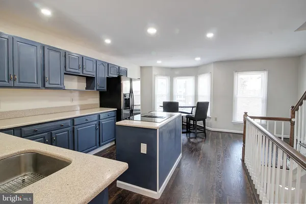 a kitchen with wooden cabinets a sink dishwasher a stove and a refrigerator with wooden floor