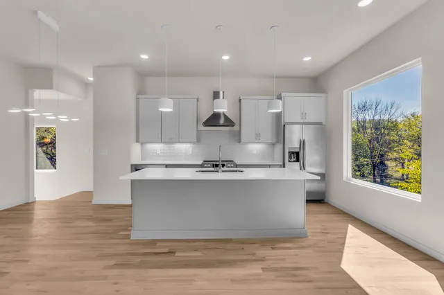 a large kitchen with stainless steel appliances a large counter top a stove and a wooden floors