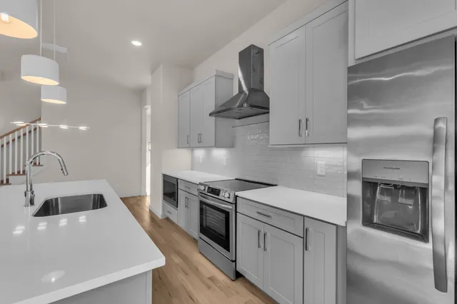 a kitchen with stainless steel appliances a sink dishwasher and a stove with wooden floor