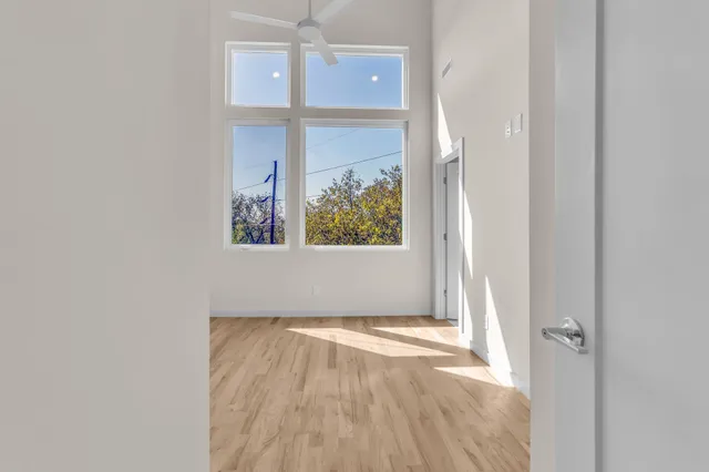 an empty room with wooden floor closet and windows