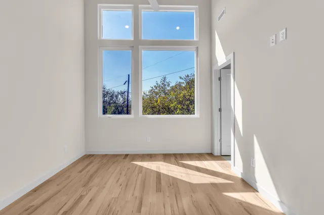 an empty room with wooden floor and windows