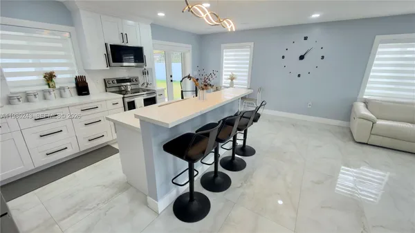 a kitchen with a microwave a stove and a dining table with wooden floor