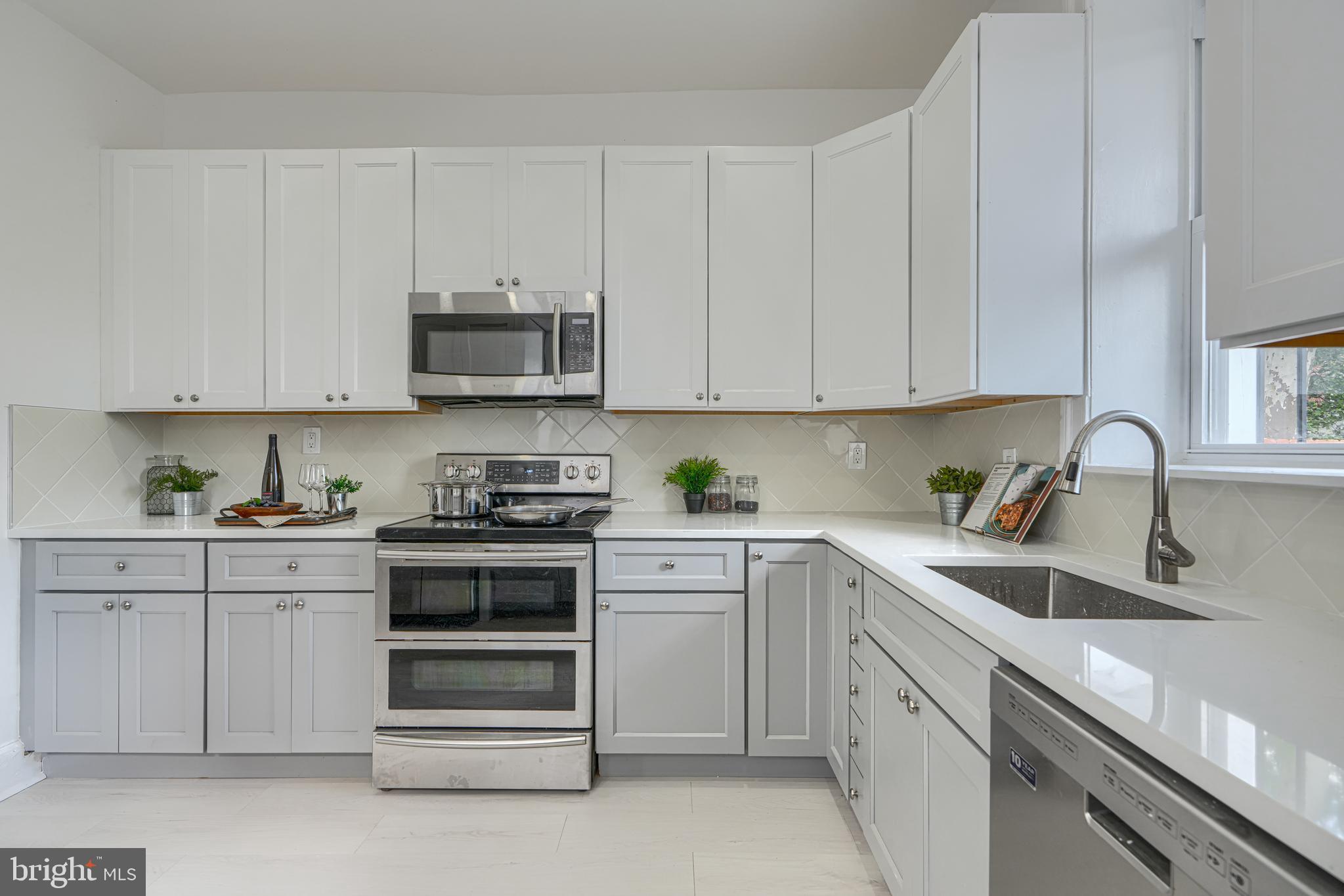 427 East 27th Street Baltimore, MD 21218 - Photo 11 of 24 a kitchen with white cabinets and stainless steel appliances
