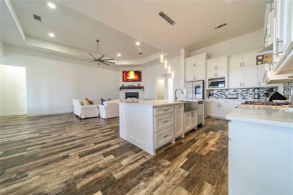 165 Ranch House Road Rockwall, TX 75032 - Photo 14 of 40 a large white kitchen with cabinets and a wooden floor
