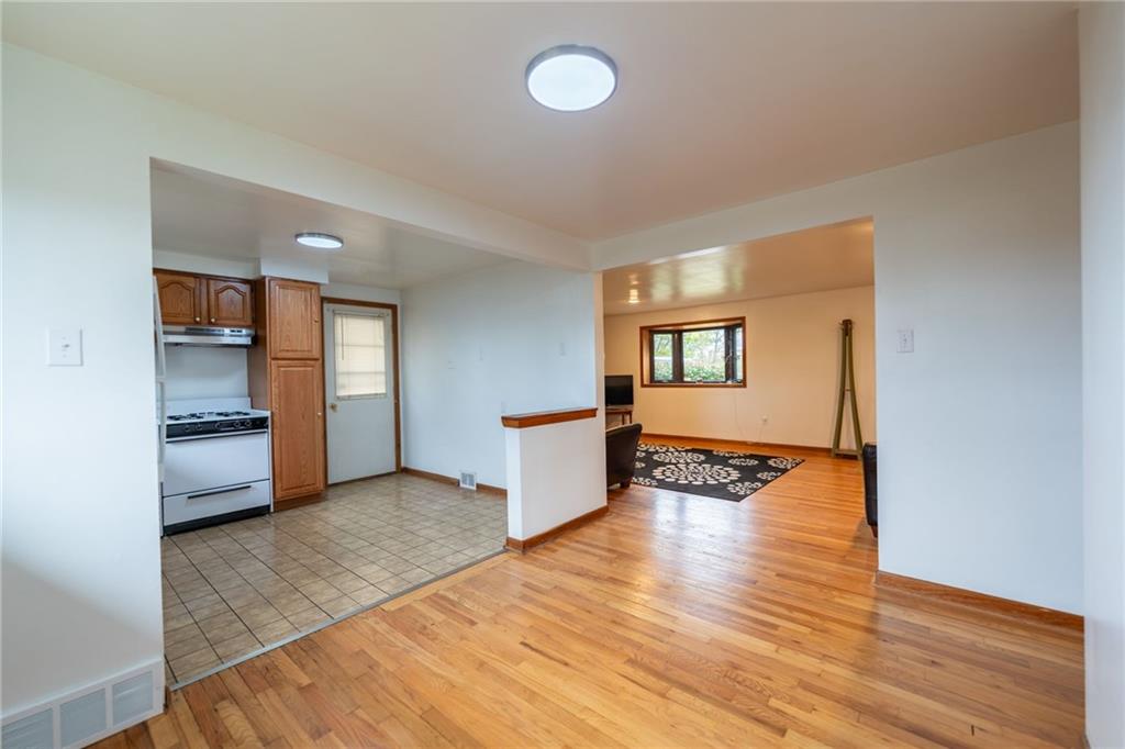 601 Hillcrest Avenue McKees Rocks, PA 15136 - Photo 8 of 32 a view of a kitchen and an empty room with wooden floor and windows