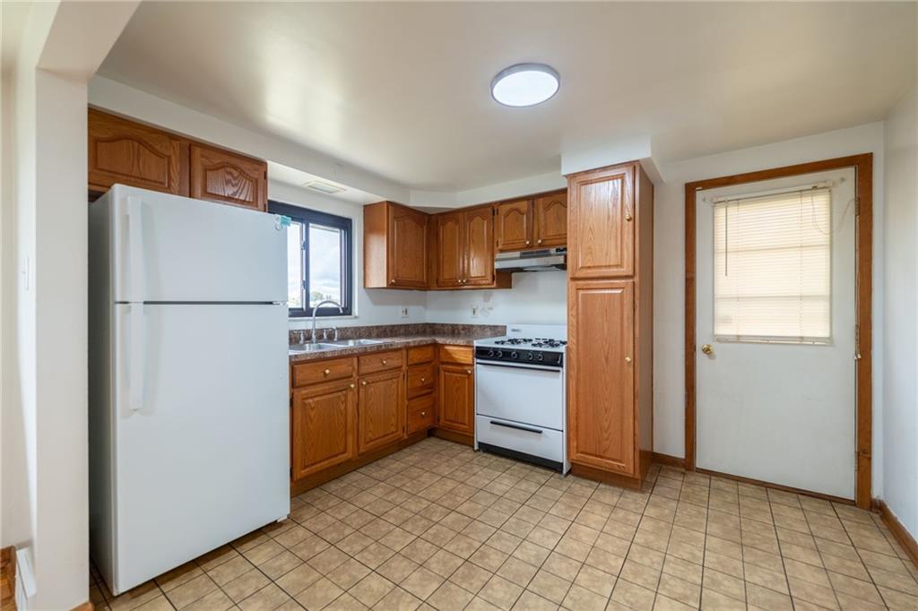601 Hillcrest Avenue McKees Rocks, PA 15136 - Photo 10 of 32 a kitchen with a refrigerator a stove top oven and cabinets