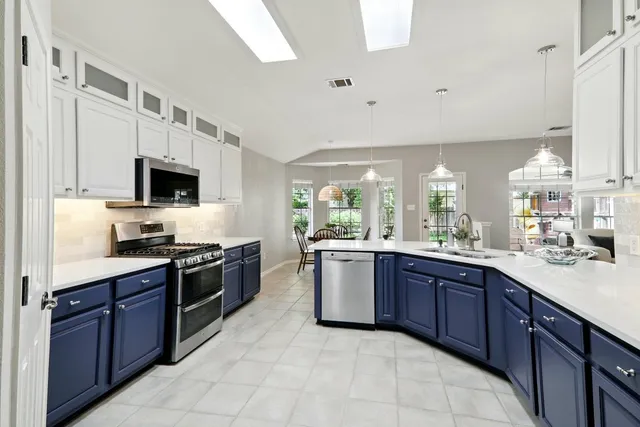 a large kitchen with stainless steel appliances granite countertop wooden cabinets a sink dishwasher a stove and a refrigerator