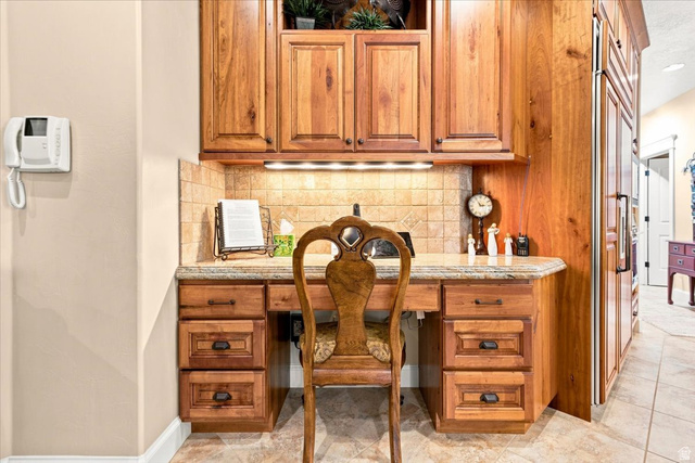 11290 South Southfield Road Mayfield, UT 84643 - Photo 50 of 103 Built-in desk featuring wood cabinetry, a tiled backsplash, under-cabinet lighting, and a stone countertop