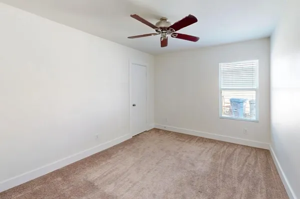 an empty room with a window and a fan