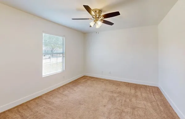 an empty room with a window and a fan