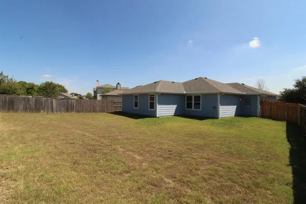 a view of a house with a yard and a large tree
